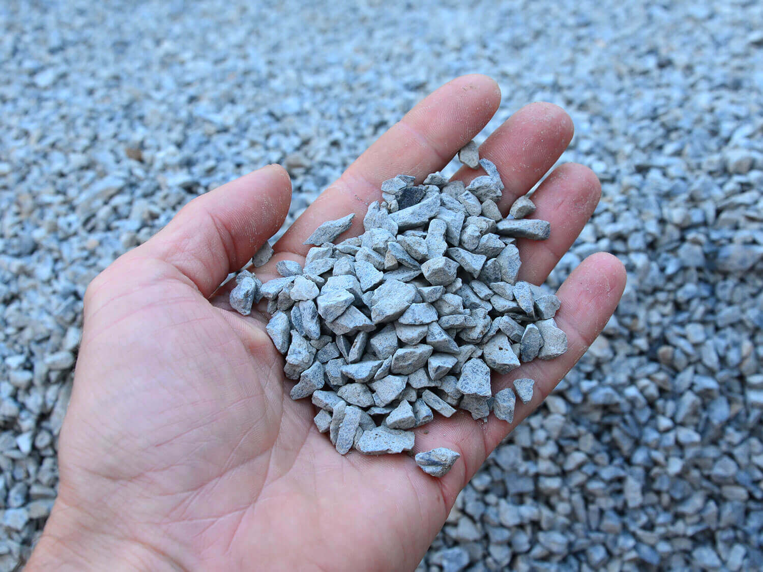 Man's hand holding a handful of crushed stone